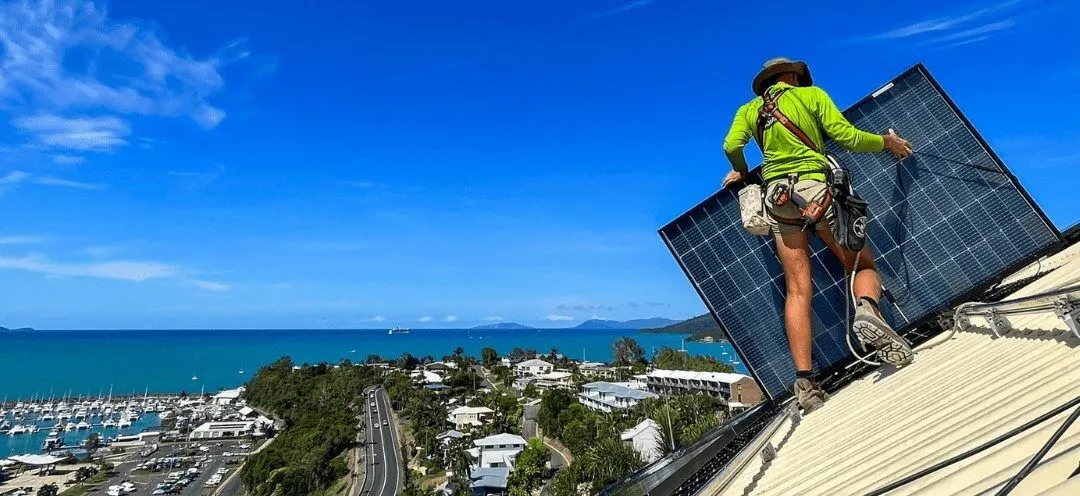 Solar installer positioning panels on a North Queensland home